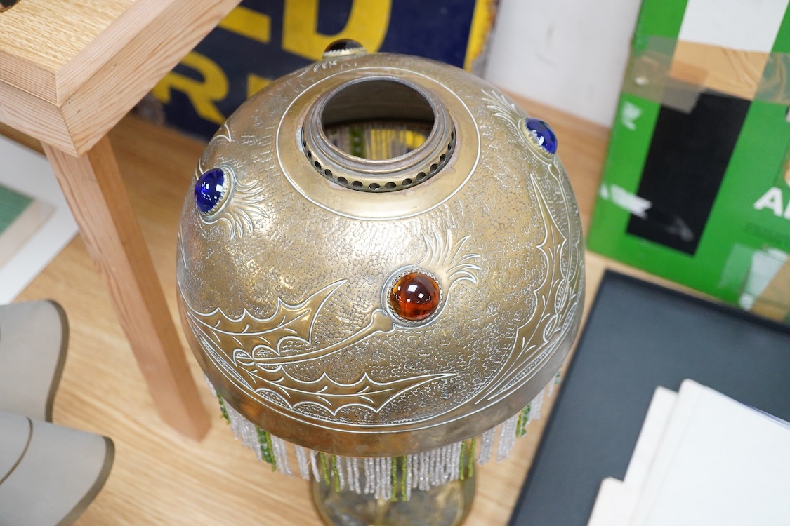 After Georges Leleu, an Art Nouveau brass oil lamp converted to electricity, with glass cabochon roundels and beaded fringing, 50cm high